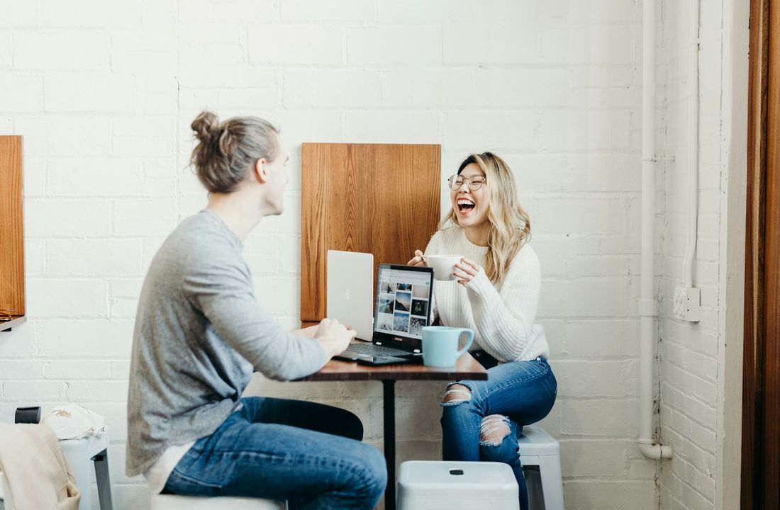Two people laughing together during a working conversation